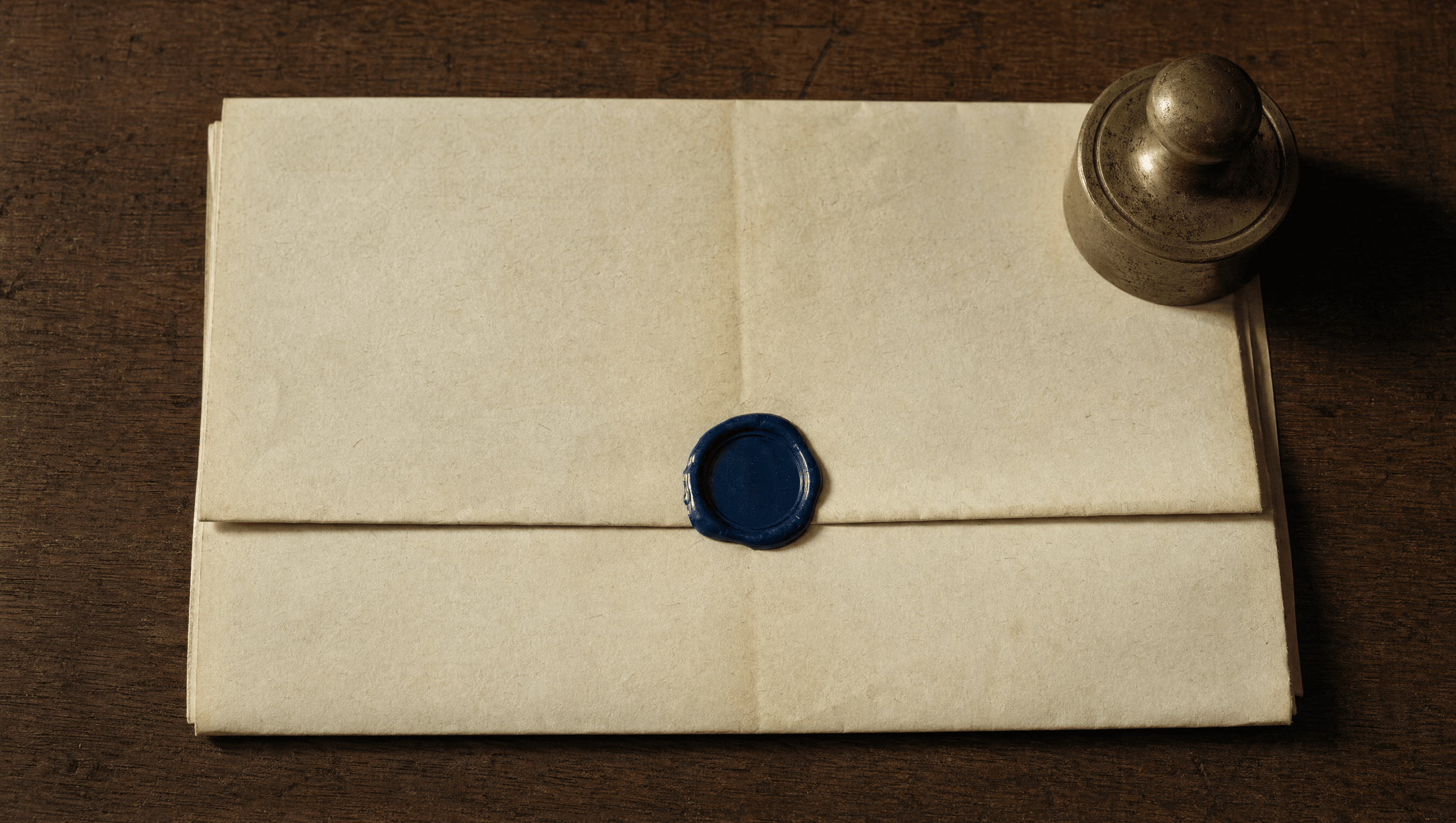 A folded legal-style document on cream paper, sealed with a small ink-blue wax seal, brass weight at the corner.